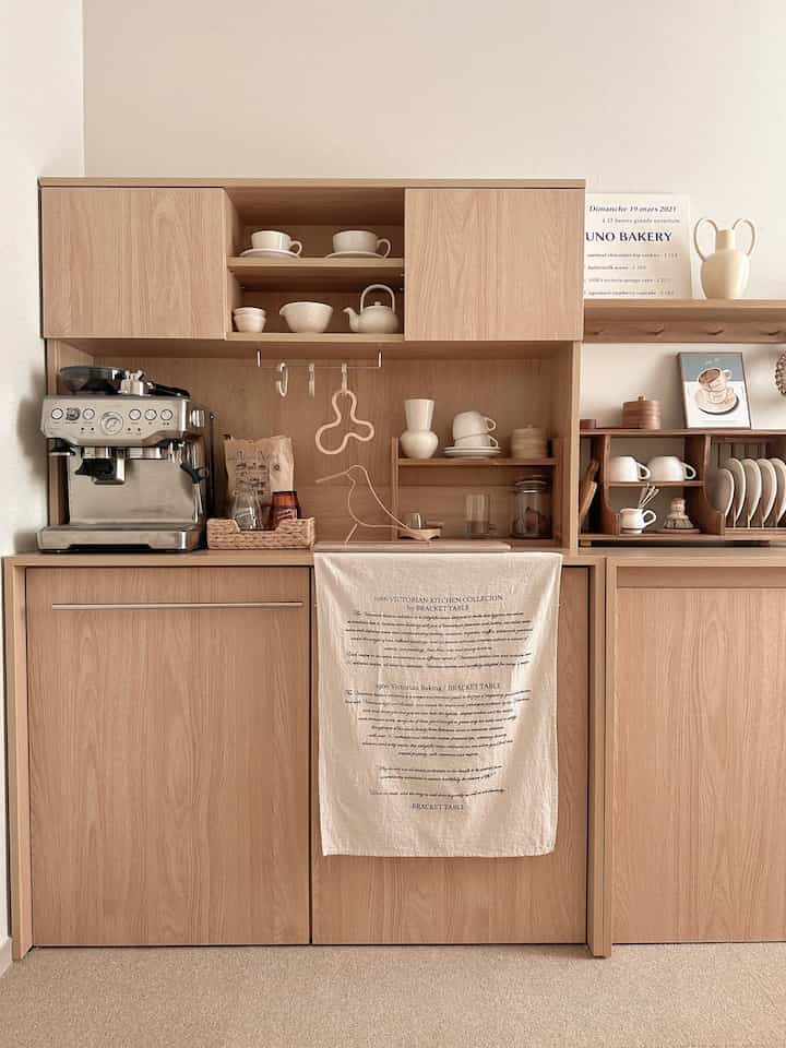 Natural wood tone small home cafe with white ceramics, ING Home cabinets and coffee machine arranged in cozy interior