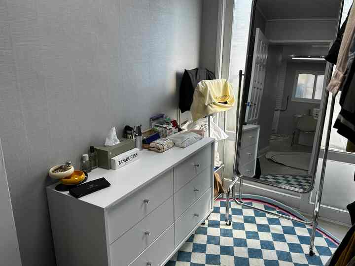 Narrow entrance space with white and blue tones featuring a dresser and standing mirror, creating a clean and simple atmosphere
