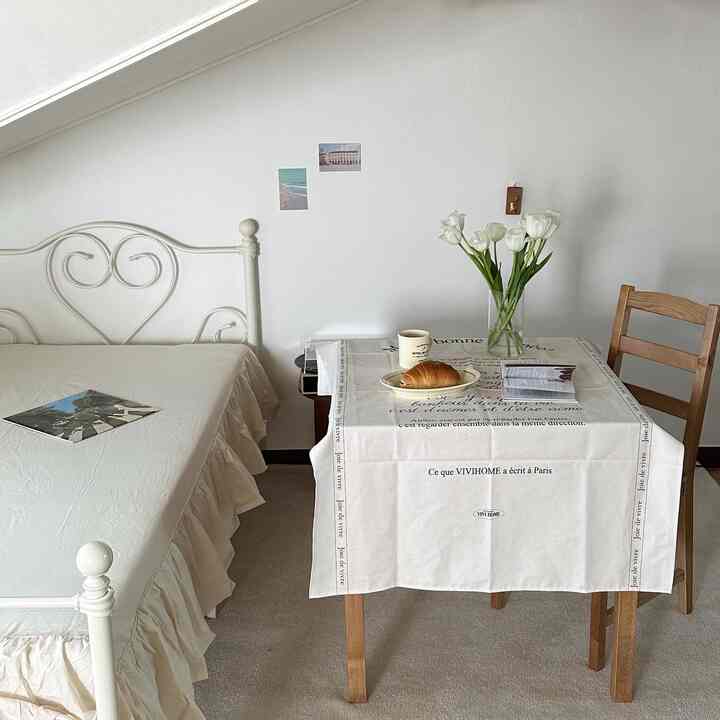 白とベージュのトーンの寝室、シンプルな家具と花瓶が置かれた小さなテーブルが印象的な落ち着いたインテリア