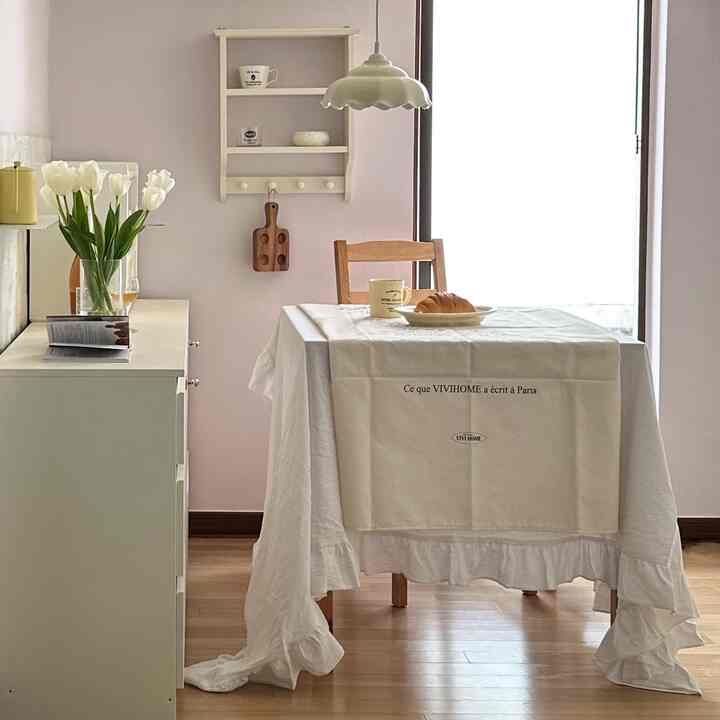 白と木目調が調和したダイニングルーム、木製の椅子とテーブルクロスが配置された雰囲気のある空間