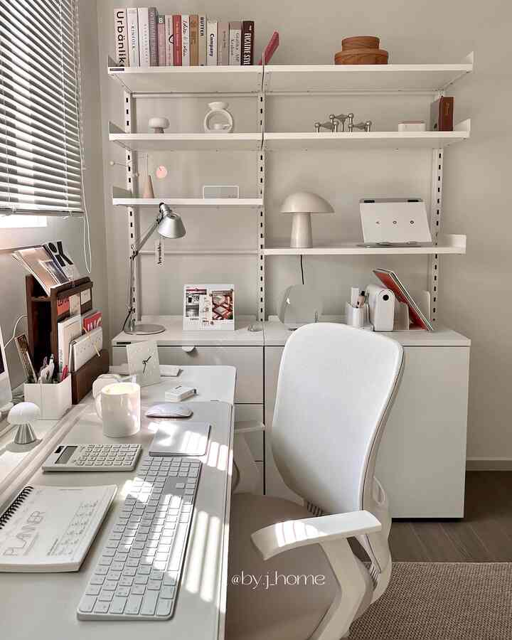 Bright white-toned study space featuring a desk, office chair, organized bookshelf, and stylish lighting in a modern home office interior