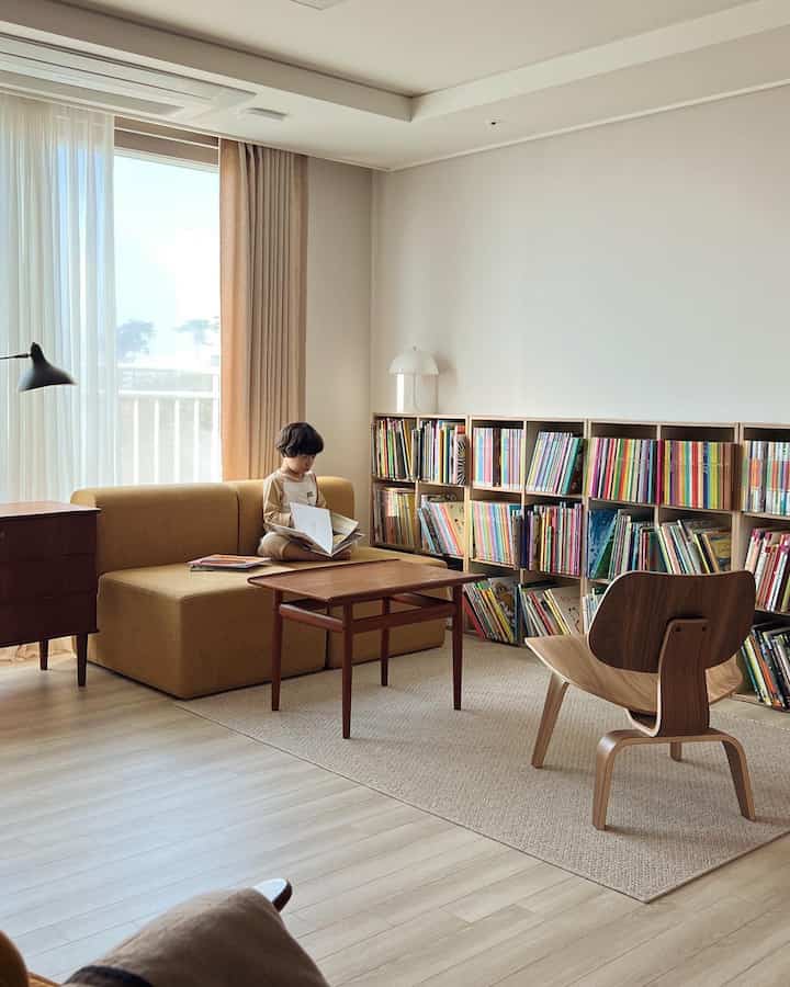 Beige and mustard toned living room and study featuring child reading area with cozy and natural interior