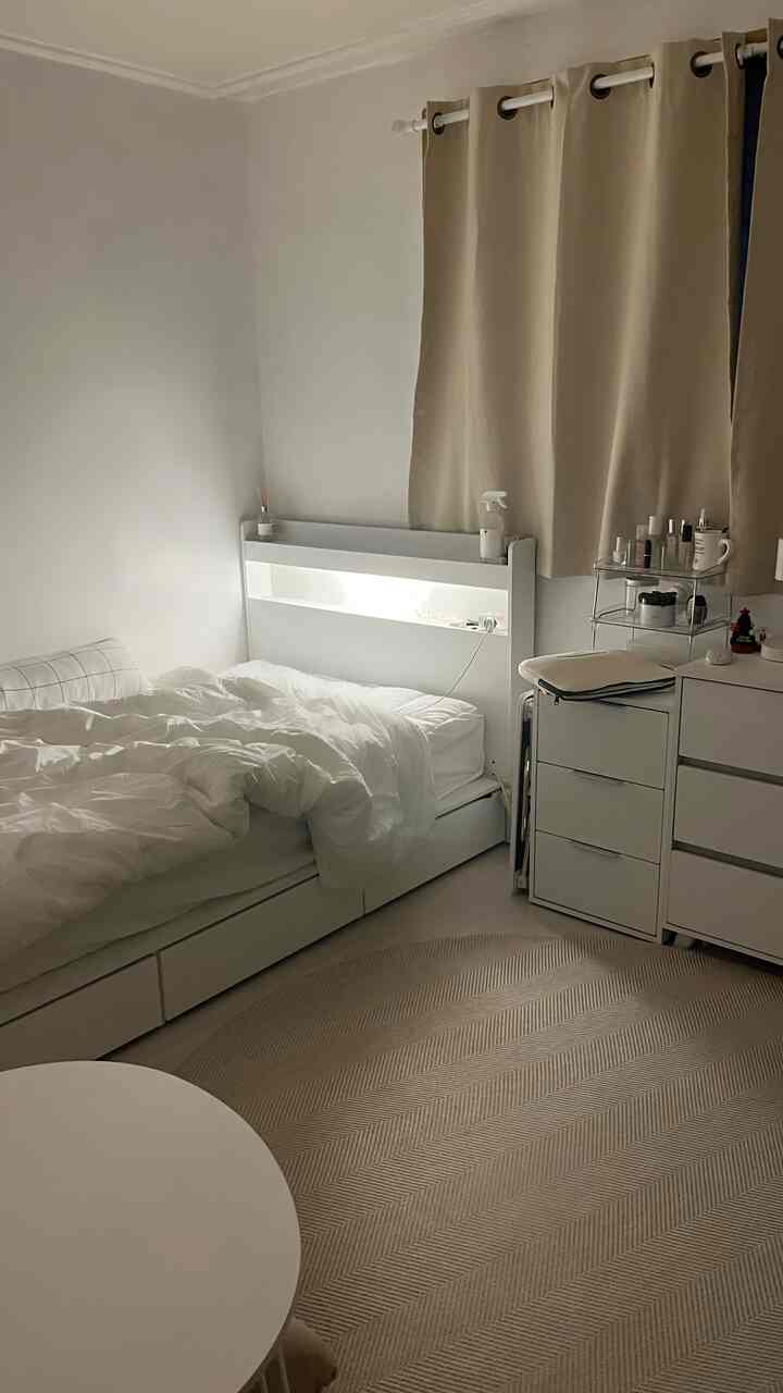 White and beige toned bedroom featuring a single bed and storage furniture in a simple layout