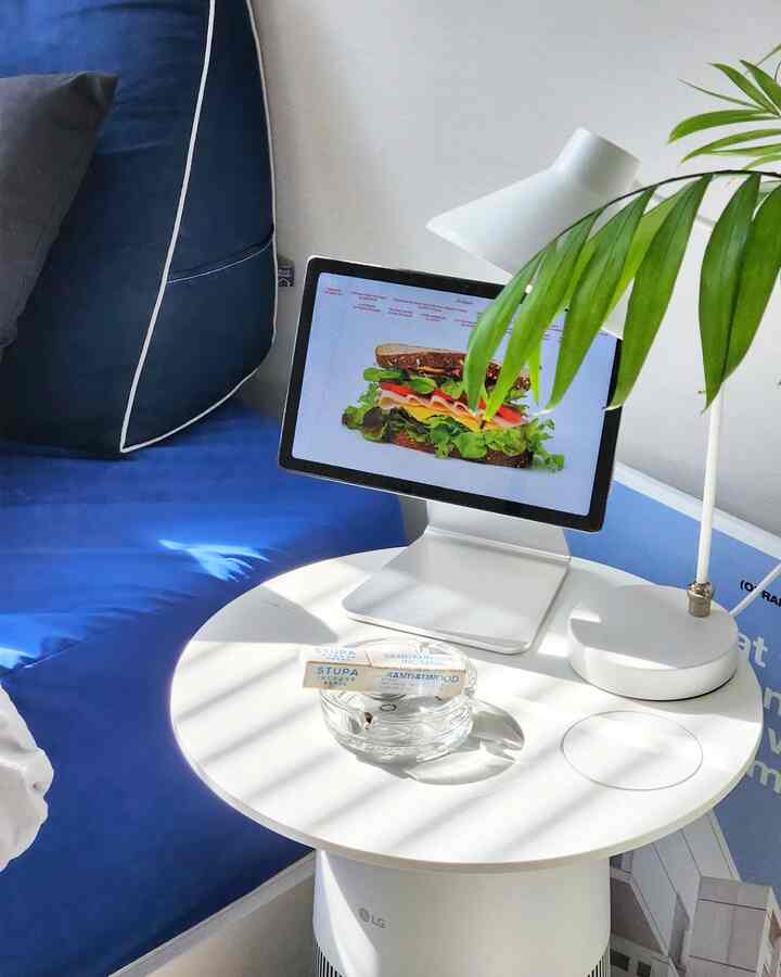 白と青のトーンのホームオフィス兼おうちカフェ空間、丸いサイドテーブルにタブレットスタンドと植物が配置されたミニマルなインテリア