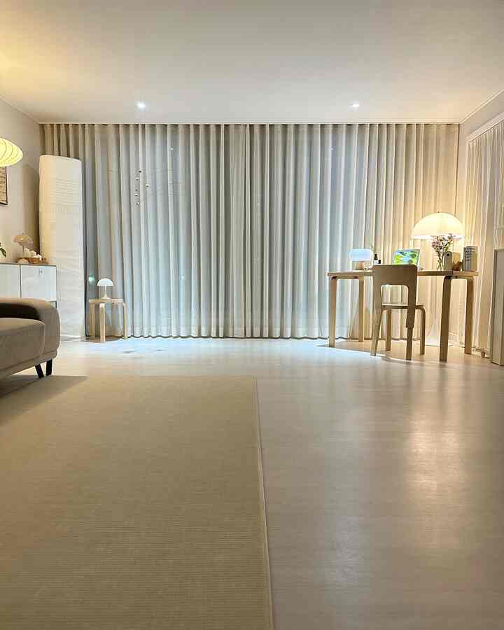 Ivory and light brown toned living room featuring wide linen curtains, wooden table and sofa for a warm natural atmosphere