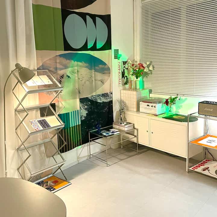 White mid-century modern studio space featuring metal cabinet and large art wall, creating a modern atmosphere