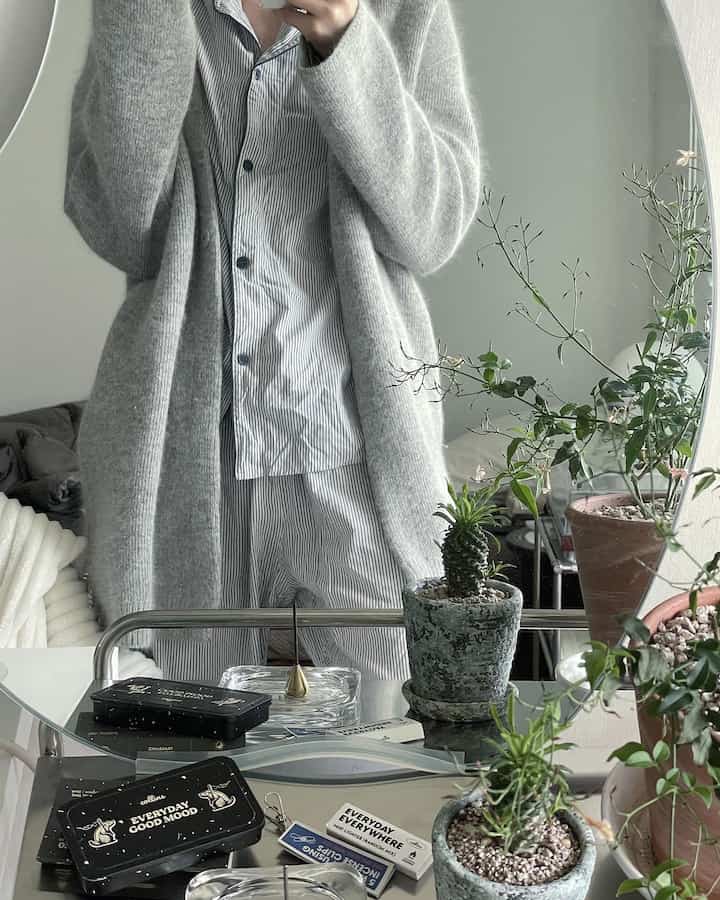 Natural-toned home office space with gray and white hues, featuring a mirror-front table with plants and incense in a simple interior