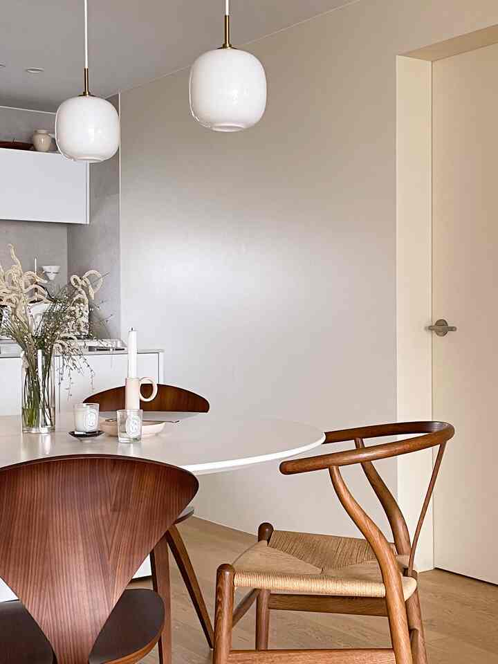 White and brown toned kitchen dining area featuring minimal dining chairs and candles on a neat round table