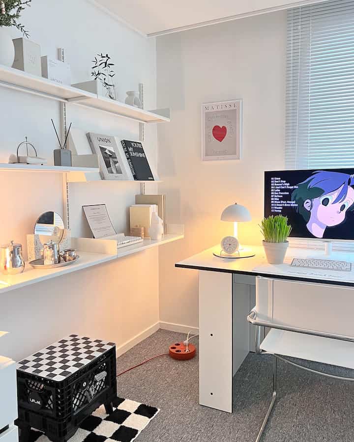 White-toned studio home office space featuring a clean desk, plants, and cat accessories with a simple ambiance