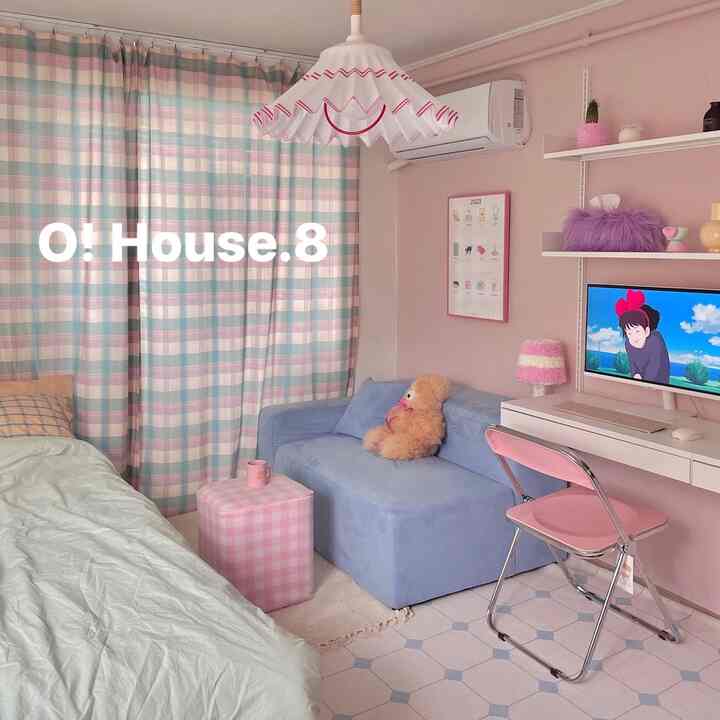 ピンクと淡いパステルブルーの色調のワンルーム、ベッドとソファ、デスク、カーテンが配置された雰囲気のあるインテリア