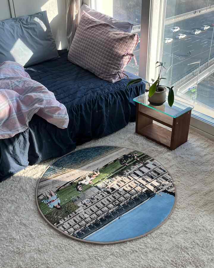 白いラグとネイビーカラーの寝具があるワンルームの寝室、大きな窓際に観葉植物を置いた陽光あふれる空間