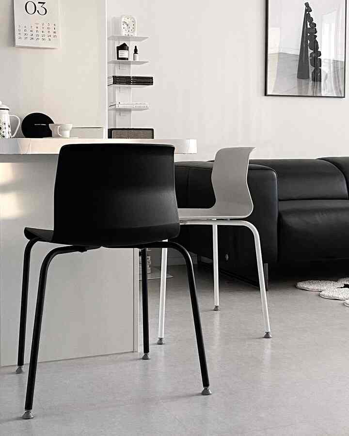 Modern living room in white and black tones featuring sleek dining chairs and a sofa with a clean aesthetic