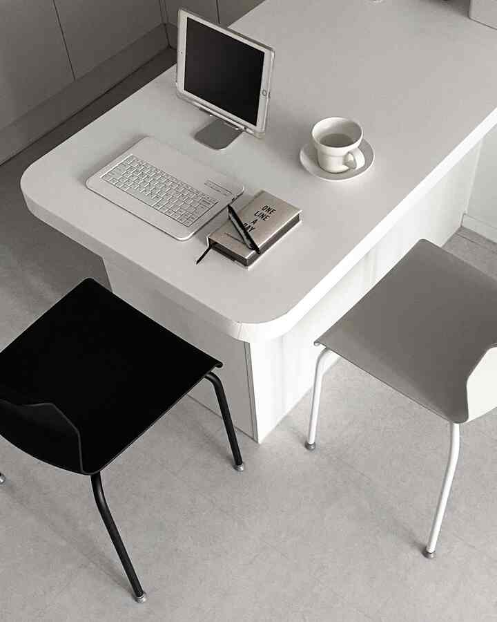 白と黒のモダンなダイニングルーム、シンプルなダイニングチェアとテーブルに置かれたタブレットがあるホームオフィス空間