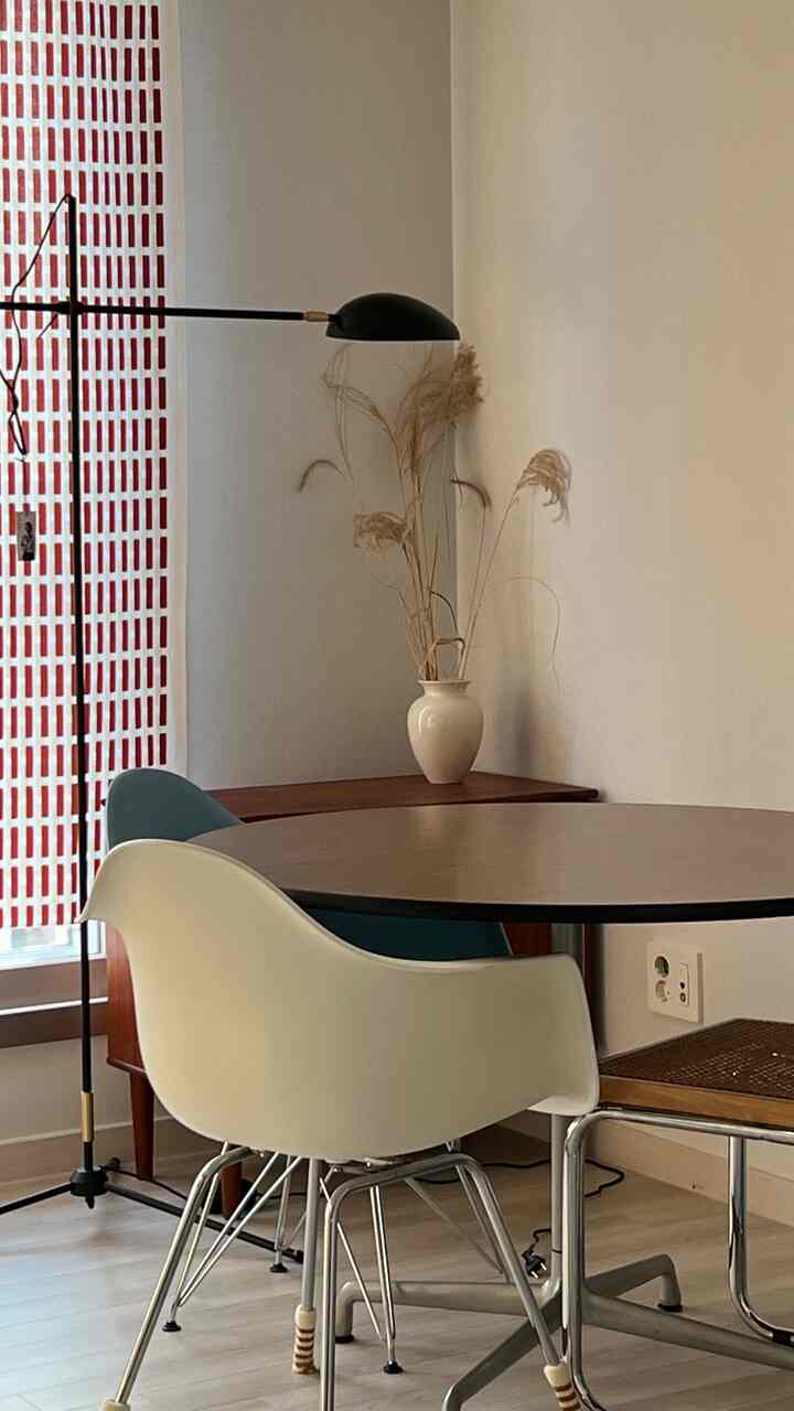 Beige-toned dining room featuring a round dining table, Nordic dining chairs, vase, and table lamp creating a cozy atmosphere