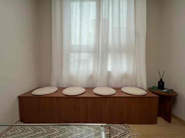 ナチュラルな木目調とベージュクッションが配置された狭いワンルームのリビングスペース