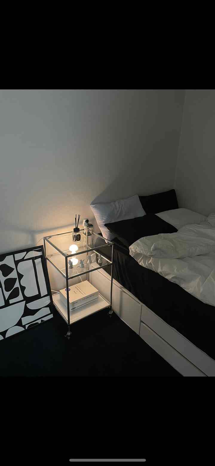 ブラックとホワイトのトーンの寝室、モダンなナイトテーブルと収納式ベッドが配置された清潔感のあるミニマルな空間