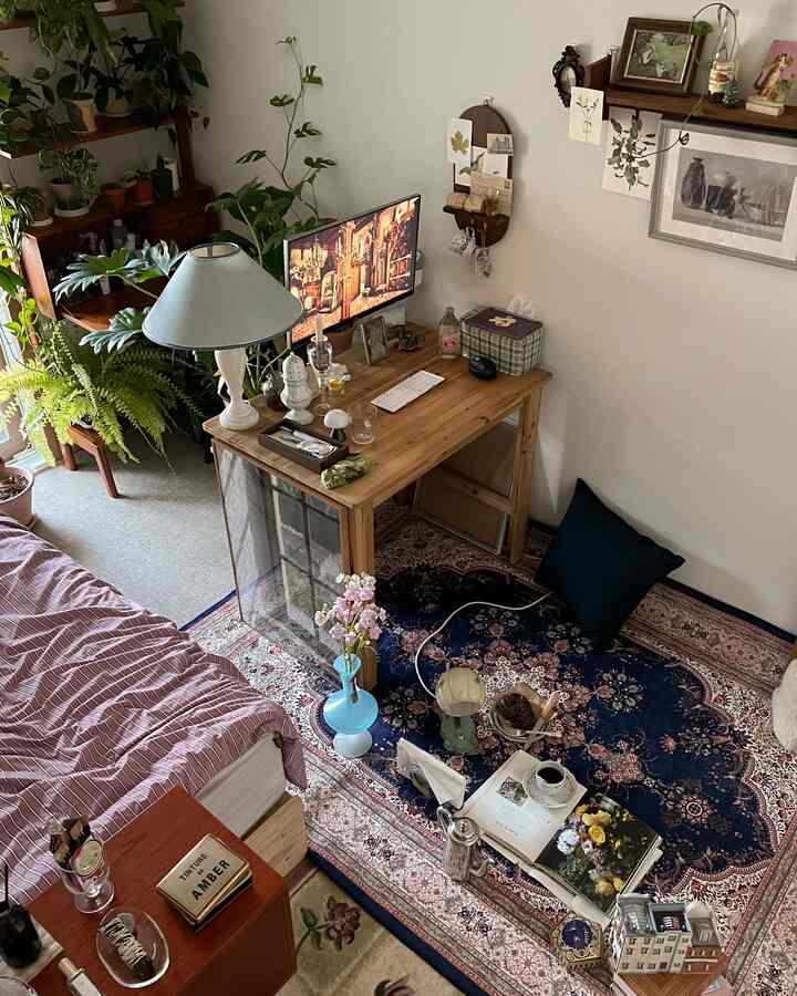 ネイビーとナチュラルな色調の寝室、ペルシャ絨毯と植物が配置された雰囲気のあるデスクインテリア