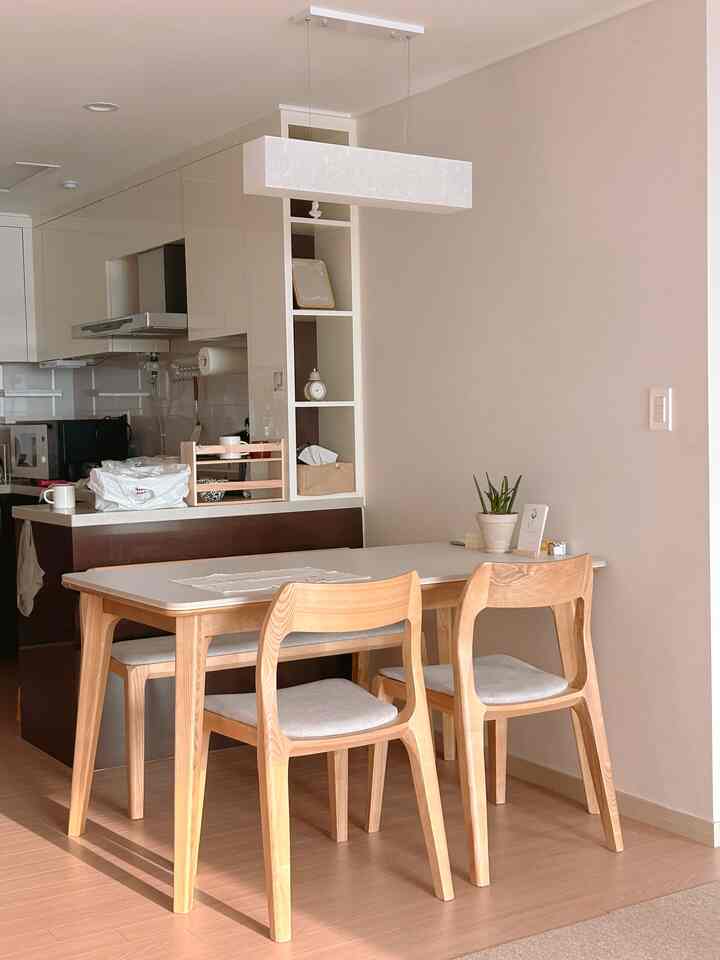 ベージュと木目調が調和した、ダイニングテーブルと椅子が配置された落ち着いたキッチン兼ダイニングの雰囲気のあるインテリア