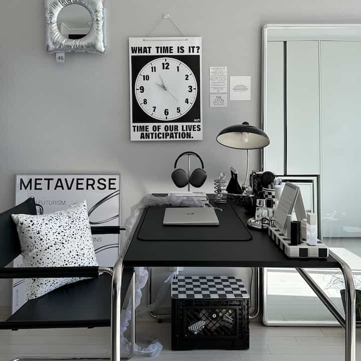 Modern home office in black and gray tones featuring a black desk, office chair, laptop, and desk lamp with a clean workspace atmosphere
