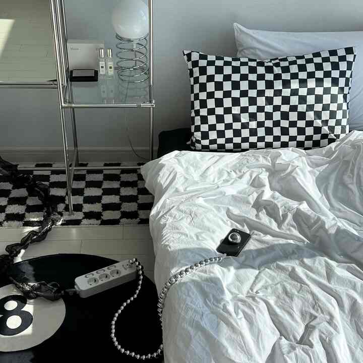Black and white bedroom featuring checkerboard pillow and rug, metal side table, creating a modern atmosphere