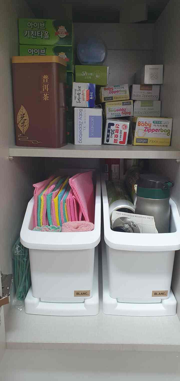 白いキッチンキャビネットの中に、きちんと整理されたさまざまなキッチン用品と収納容器が配置された雰囲気のあるインテリア