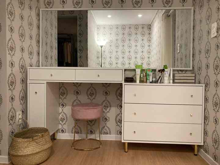 White and wood-tone powder room featuring large mirror, vanity, and pink stool in a cozy interior