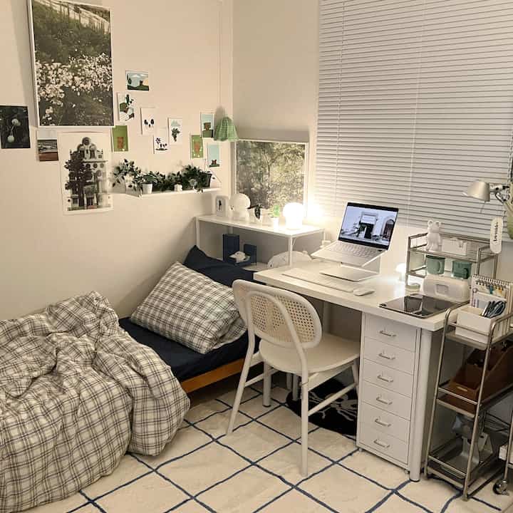 ホワイトとブルーの色調が特徴の寝室兼ホームオフィス、チェック柄の寝具とデスクが配置された落ち着いた空間