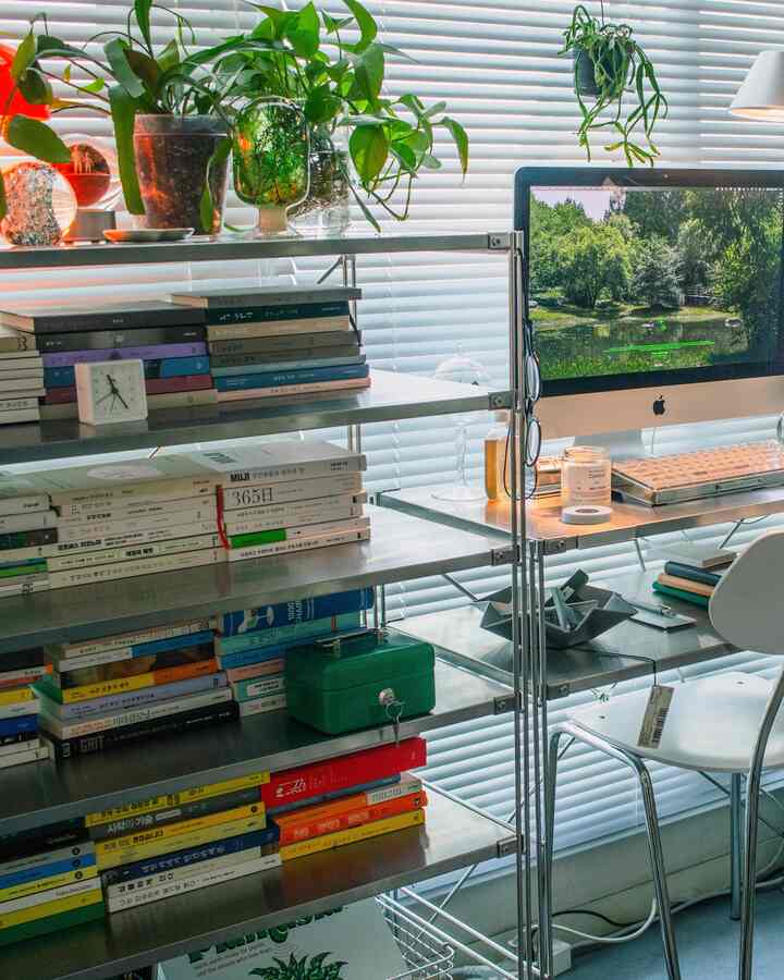 ホワイトとシルバーのトーンのホームオフィス、金属製の棚と本棚が配置された整理された作業空間