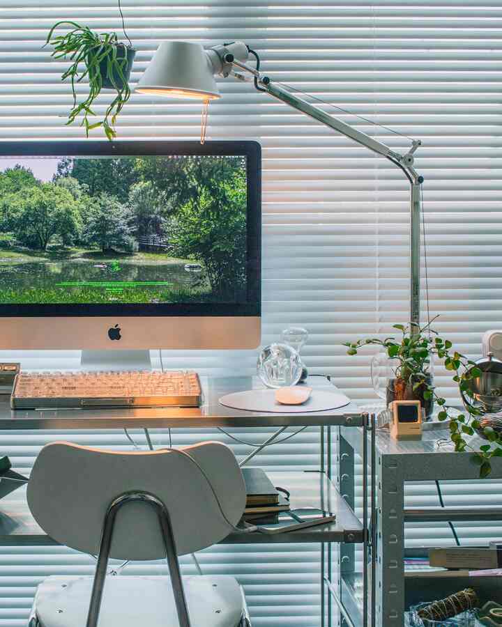 シルバーのトーンが印象的なコンパクトなホームオフィス、モダンなデスクとオフィスチェア、照明が配置された清潔感ある作業空間