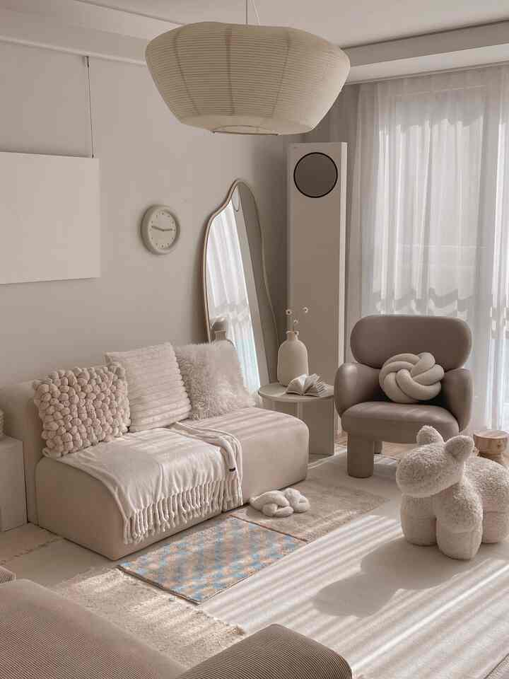 Warm beige living room featuring a simple sofa, armchair, large mirror, and side table arranged for cozy minimalism
