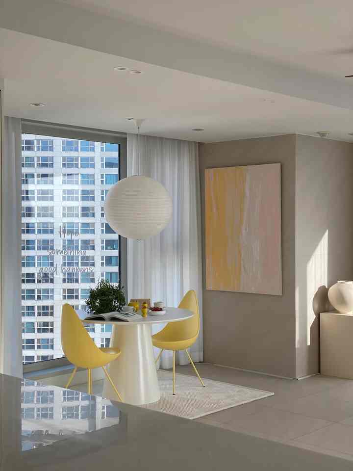 Bright yellow and white toned dining room with a round table and yellow dining chairs, showcasing a simple and natural atmosphere