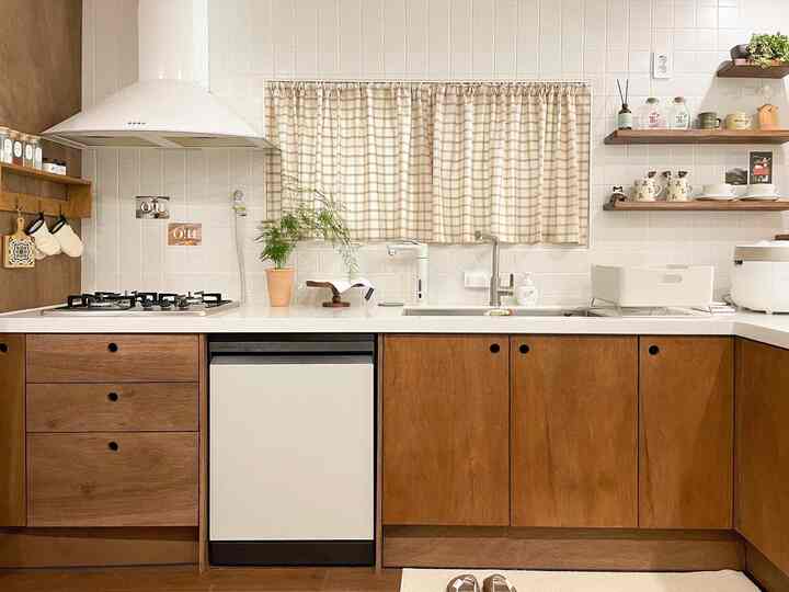 ベージュのチェック柄バランスカーテンと木目調の下部収納、白いタイルが調和した温かみのあるモダンなキッチン