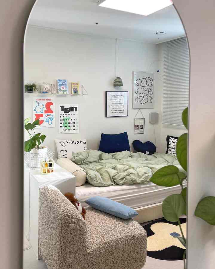 ホワイトとネイビーのトーンが特徴の小さな寝室、ベッドやクッション、デスクが配置された落ち着いたインテリア