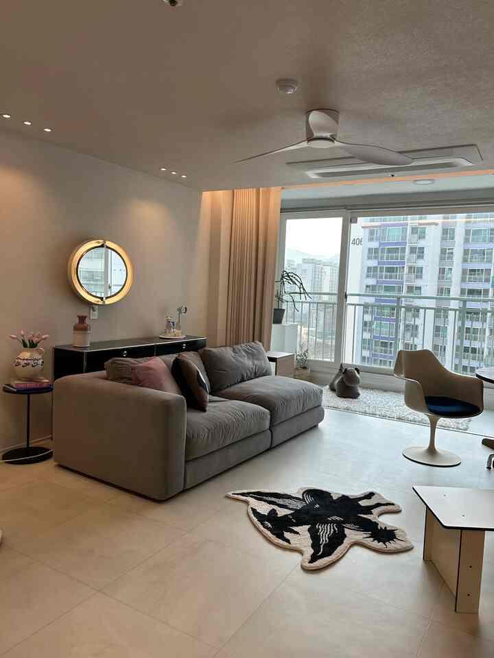 Gray sofa and beige curtains in a living room featuring a ceiling fan and wall lighting, creating a modern atmosphere