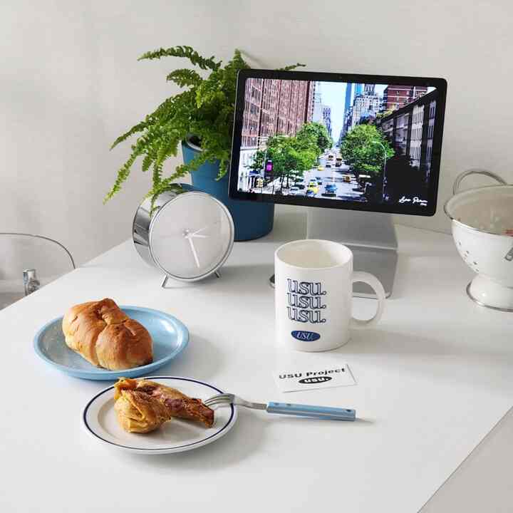 白いテーブルに青い皿とマグカップ、時計、植物が配置されたコンパクトなおうちカフェ空間