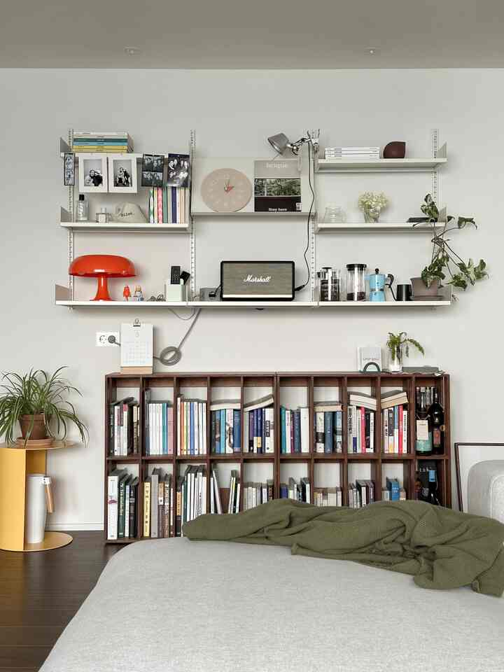 Natural color tone living room featuring bookshelves, wall shelves with decor and plants, creating a simple Nordic style space