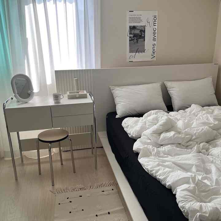 白と黒を基調とした寝室、シンプルな化粧台とポスターが配置された印象的な空間