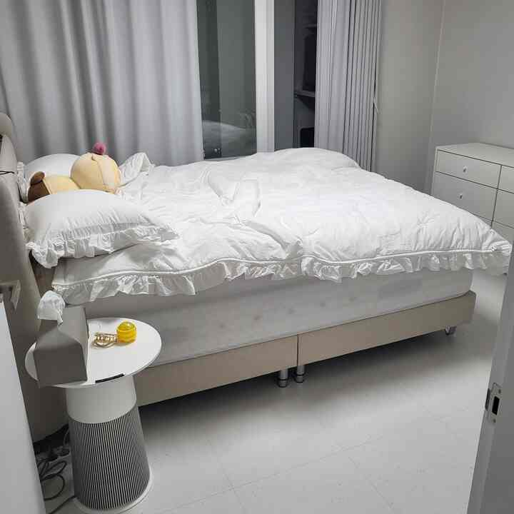 White and beige toned bedroom featuring bed, curtains, and dresser creating cozy atmosphere