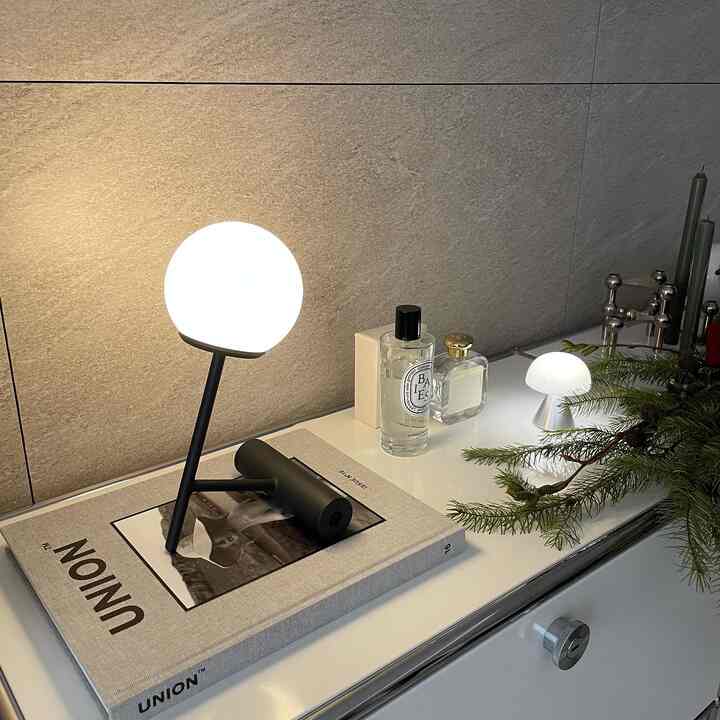 A cozy lighting interior space featuring Nordic style table lamps and objets arranged on a white and beige toned sideboard