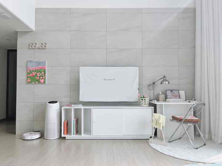 Living room with light gray walls and white furniture, featuring a workspace and a clean atmosphere