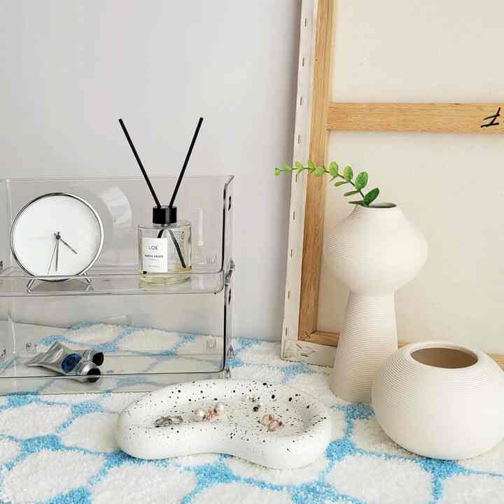 Clean modern space featuring small white and ivory interior accessories arranged neatly on a patterned surface