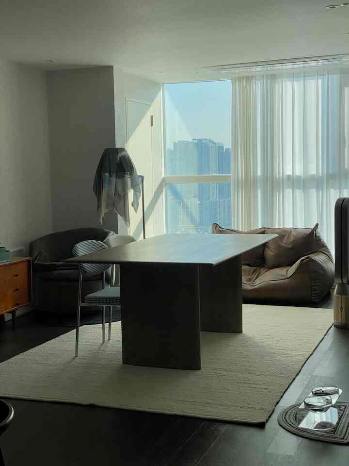 明るい白色調のリビング、大きなテーブルとブラウンのビーズクッションが配置された自然でモダンな空間