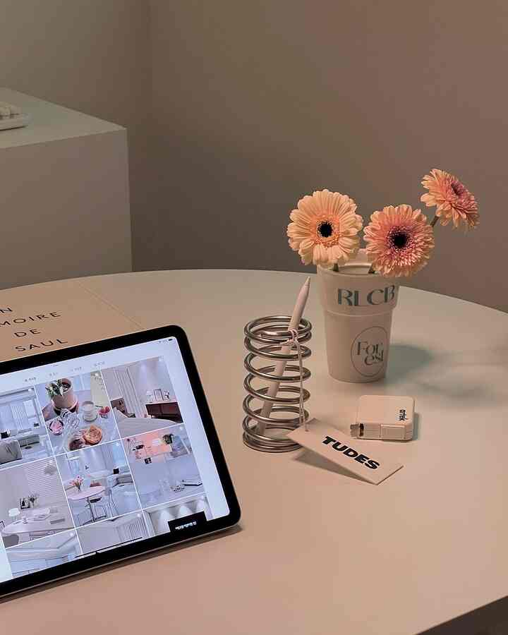 Minimal indoor space with a white round table featuring a digital device and a flower vase