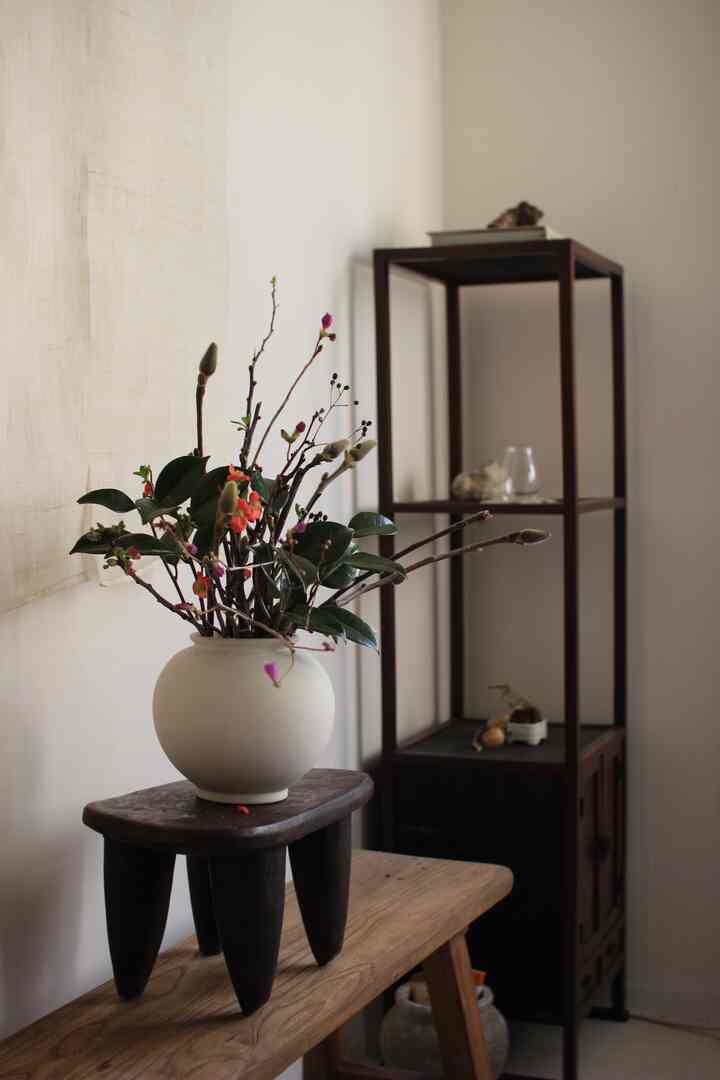 A natural-toned small space in white and brown, featuring antique wood furniture and a moon jar vase with arranged flowers