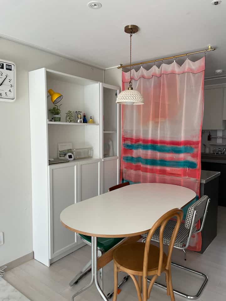 Bright white-toned kitchen and dining area with colorful chiffon curtain room divider creating a cozy atmosphere