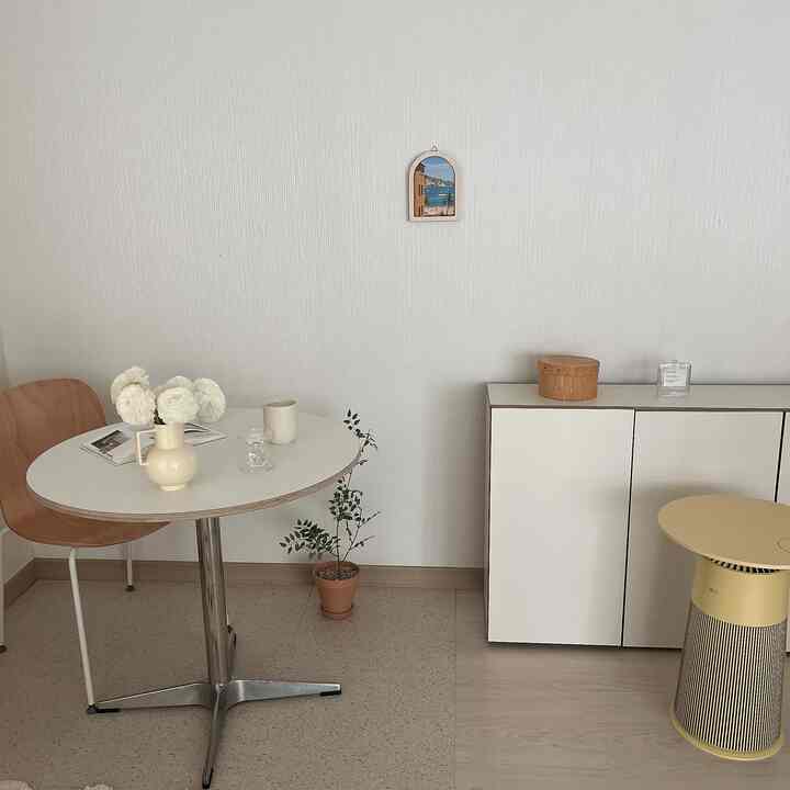 A white and beige toned natural modern cafe style space featuring a round dining table and cabinet with a clean, minimalist interior