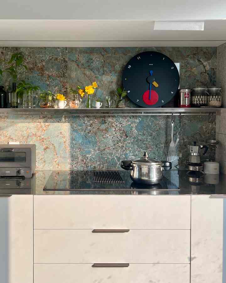 グレーのキッチンキャビネットと黒いIHコンロ、透明な花瓶に黄色い花が飾られた自然感のあるキッチン