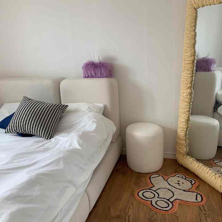 White and brown toned bedroom featuring a bouclé stool and large textured mirror with cozy atmosphere