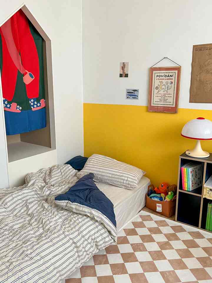Yellow-walled and white-background kids' room featuring a bed, bookshelf, and toy storage basket in a cozy setting