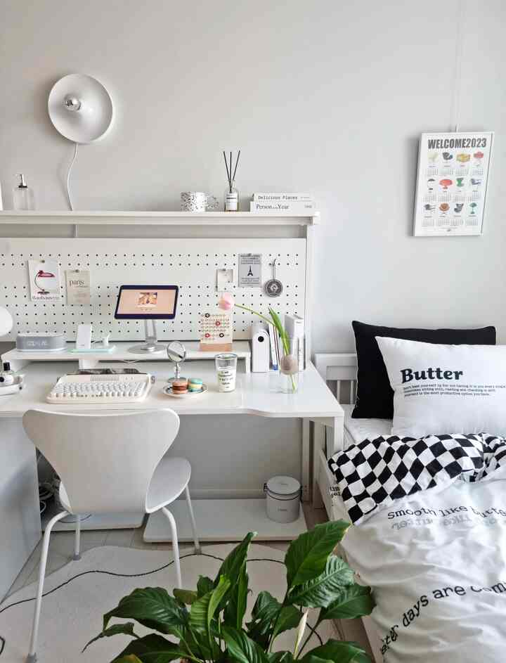 白と黒のトーンの子供部屋、子供用机とベッド、植物が配置された清潔感のある明るい空間